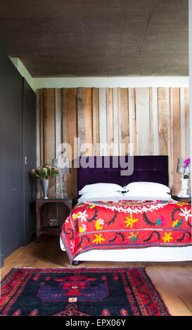 Letto con viola scuro testiera e messicano ispirato tiro con tappeto persiano, Sud Africa home Foto Stock