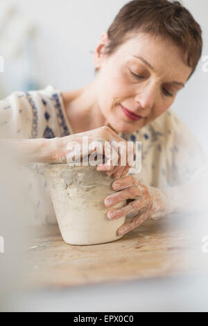 Senior donna che fa il vaso di fiori in officina Foto Stock