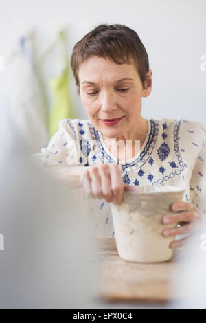 Senior donna che fa il vaso di fiori in officina Foto Stock