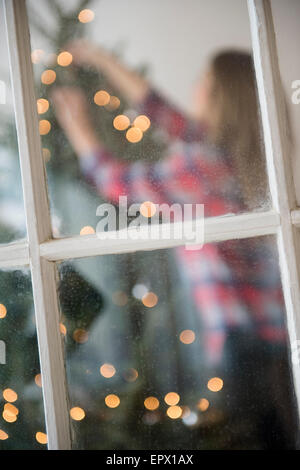 Giovane donna decorare albero di natale Foto Stock