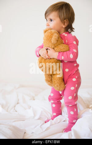 La ragazza (2-3) abbracciando orsacchiotto sul letto Foto Stock