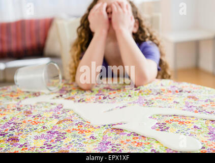 Ragazza triste (10-11) versato fuori il latte Foto Stock