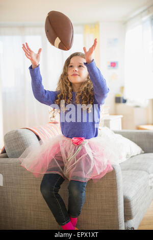 La ragazza (10-11) indossando tutu giocando con il calcio Foto Stock