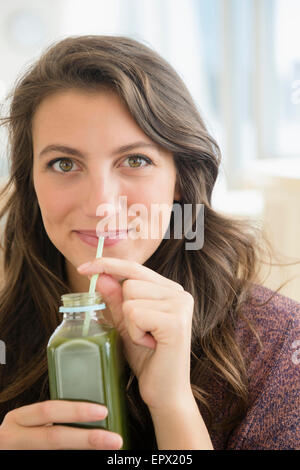 Ritratto di donna di bere succo di frutta da bottiglia con paglia Foto Stock