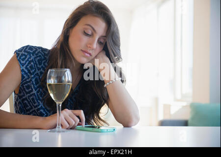 Triste donna con bicchiere di vino texting Foto Stock