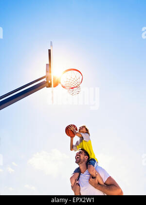 Ragazzo (8-9) giocare a basket con suo fratello Foto Stock