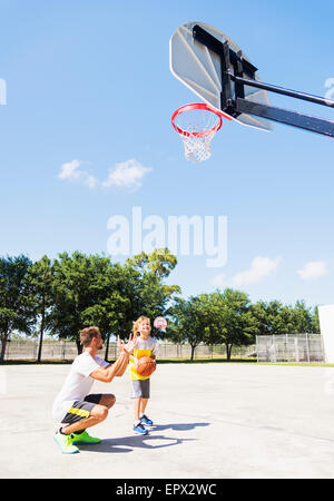 Ragazzo (8-9) giocare a basket con suo fratello Foto Stock