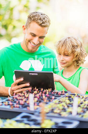 Ragazzo (8-9) utilizzando tablet pc con suo fratello in giardino Foto Stock