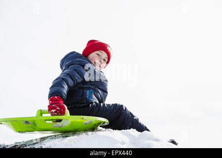 Ragazzo (6-7) slittino in inverno Foto Stock