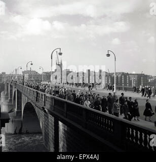 Degli anni Cinquanta, foto storiche, guardando verso sud, vediamo pendolari camminando sul Ponte di Londra, con nuovo Hibernia Wharf e la Southwark Cathedral in background, Londra, Inghilterra, Regno Unito. Foto Stock