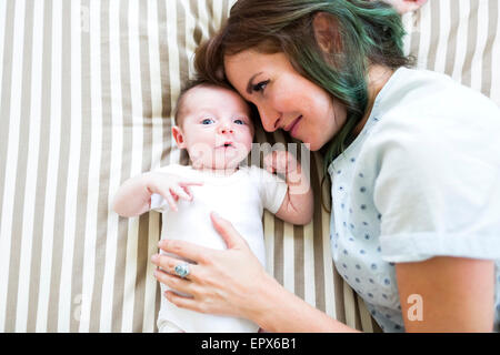 Sorridente madre giacente sulla cattiva con baby boy (6-11 mesi) Foto Stock