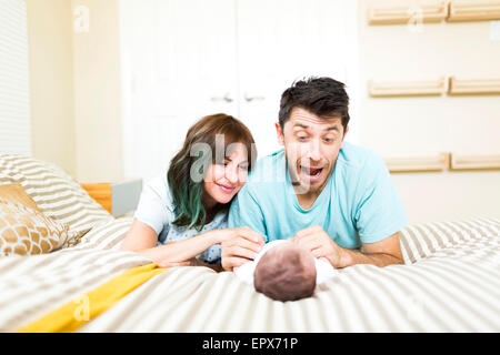 Genitori felici giocando con il bambino (6-11 mesi) sul letto Foto Stock
