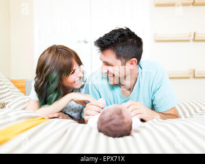 Genitori felici giocando con il bambino (6-11 mesi) sul letto Foto Stock