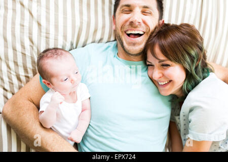 Genitori felici con baby boy (6-11 mesi) giacente sul letto Foto Stock