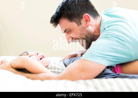 Padre giocando con la figlia (4-5) sul letto Foto Stock