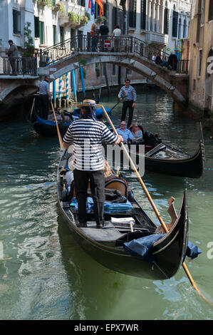 Venezia, Italia - 24 Aprile 2013: gondoliere veneziano sterline il suo passato in gondola un altro su un piccolo canale. Foto Stock