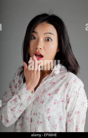 Attraente ragazza asiatica nel suo ventenne isolato su un sfondo plein girato in uno studio Foto Stock