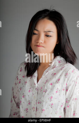 Attraente ragazza asiatica nel suo ventenne isolato su un sfondo plein girato in uno studio Foto Stock