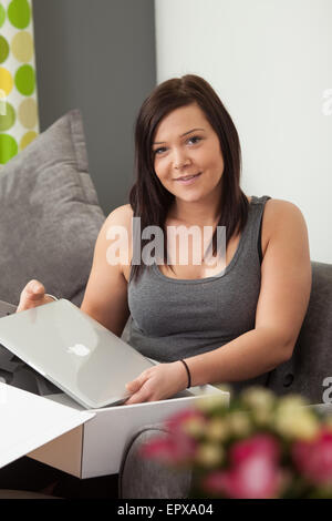 Giovane donna di prendere un nuovo notebook dal suo imballaggio. Foto Stock