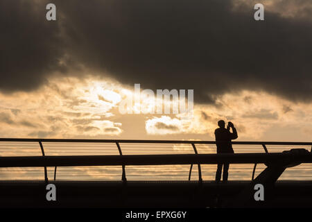 Londra, Regno Unito. 22 Maggio, 2015. Un uomo prende una fotografia come egli si stagliano contro un tramonto spettacolare sky su London Millenium Bridge Credito: Patricia Phillips/Alamy Live News Foto Stock