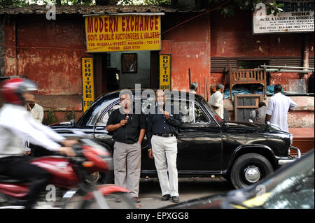 INDIA Westbengal Calcutta Kolkata, alle persone di mangiare il gelato in parte anteriore del nero HM Ambassador auto/ INDIEN Westbengalen Megacity Kalkutta, Menschen essen Sie vor HM Ambassador Auto in der Russell Street Foto Stock