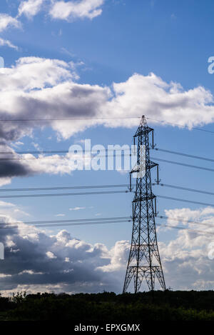 L'immagine verticale di elettricità pilone contro una drammatica nuvoloso cielo blu. Foto Stock