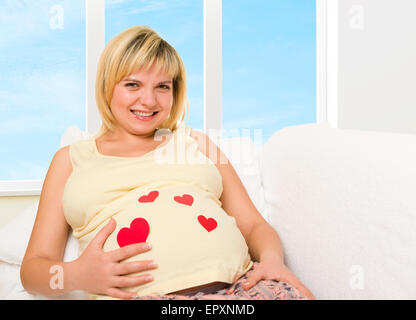 Donna incinta in letto con cuore rosso forma Foto Stock