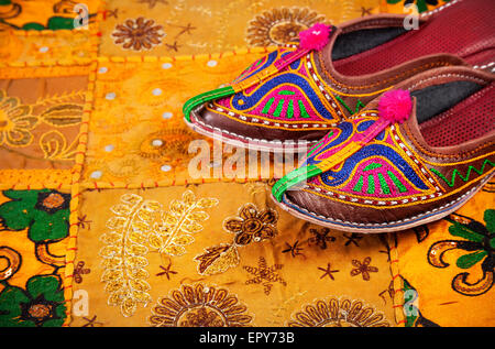 Colorate scarpe etniche su giallo Rajasthan fodera per cuscino sul mercato delle pulci in India Foto Stock