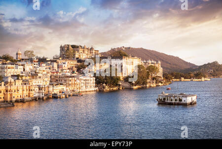Lago Pichola con City Palace vista a nuvoloso tramonto Cielo in Udaipur, Rajasthan, India Foto Stock