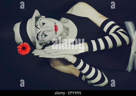 Dormire mime nel cappello bianco con fiore rosso su sfondo nero Foto Stock