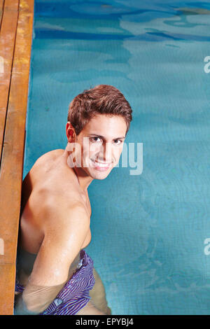 Sorridente giovane uomo in piedi sul bordo della piscina Foto Stock