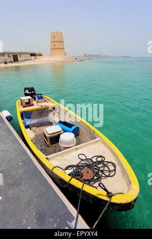 Vista la torretta al Al Dar beach resort, con una barca da pesca in primo piano in una giornata di sole, Regno del Bahrein Foto Stock