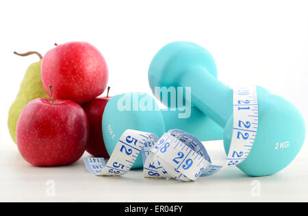 Salute e fitness concetto con blue manubri, metro a nastro e frutta fresca su bianco invecchiato tavolo di legno dello sfondo. Foto Stock