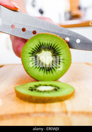 Donna taglio mani fresche Kiwi in cucina Foto Stock