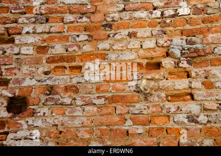 Vecchia parete in muratura che mostra molto usurati, esposto di mattoni e malta Foto Stock