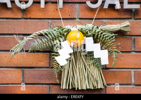 Tipico decorazione di nuovo anno, Shimekazari, posto da porte esterne in Giappone. In paglia di riso, shimenawa, strisce di carta a zigzag, foglie di shide e pino. Foto Stock