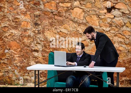 Due ragazzi intorno ad una scrivania in un ufficio di grunge, un concetto di fallimento Foto Stock