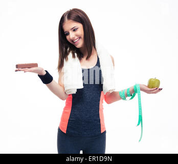 Donna sorridente rendendo la scelta tra le banane e cioccolato isolato su uno sfondo bianco Foto Stock