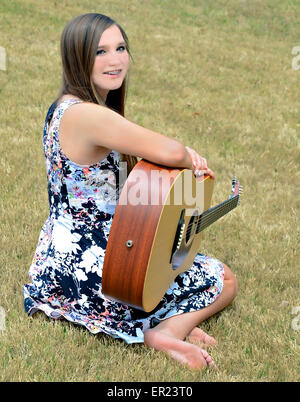 Una giovane e bella ragazza, con bretelle, all aperto con una chitarra. Foto Stock