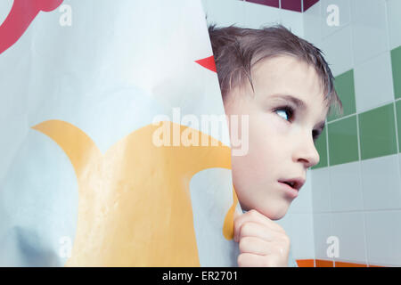 Ragazzo di 8 anni dietro la tenda della doccia Foto Stock