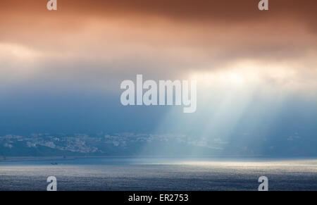 Volume la luce del sole passa attraverso di colore arancione scuro nuvole. Baia di Tangeri, Marocco, Africa Foto Stock