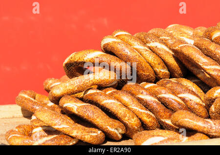 Impilati semi di sesamo simit rivestito, Turksih pane tondo contro uno sfondo rosso, Istanbul, Turchia Foto Stock