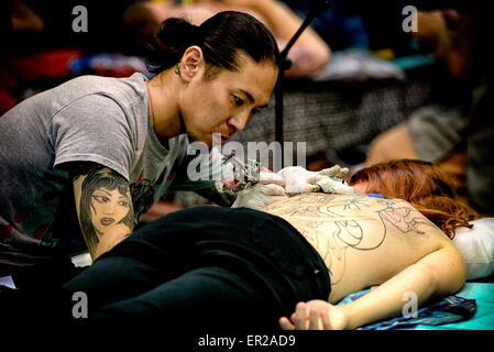 Il decimo International London Tattoo Convention il 26/09/2014 presso il tabacco Dock, Londra. Persone nella foto: un tatuaggio artista lavora su un womans indietro. Foto di Julie Edwards Foto Stock