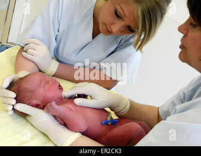 Testa infermiera consegna Karin Ruddat (R) fornisce consulenza ostetrica apprendisti Susann (C) e Ulrike su come eseguire un esame iniziale su un neonato in sala parto dell'ospedale universitario di Lipsia, in Germania, il 22 aprile 2015. Il unamolla ostetriche sono due dei 20 studenti nel loro secondo anno di loro 3 anno di apprendistato presso il Medizinische Berufsfachschule (lit. Medical Scuola Professionale) dell'università. Foto: Waltraud Grubitzsch/dpa Foto Stock