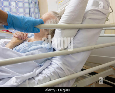 Figlio e accompagnatore visita anziana madre nel suo degli anni novanta in ospedale NHS in Inghilterra, Regno Unito Foto Stock