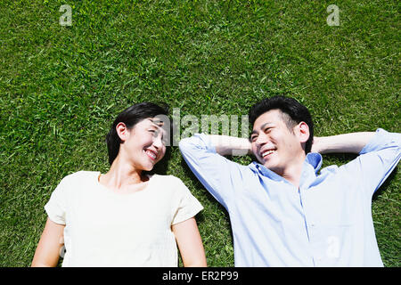 Felice coppia giapponese posa su erba in un parco