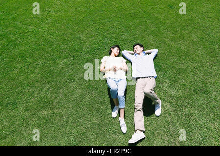 Felice coppia giapponese posa su erba in un parco Foto Stock