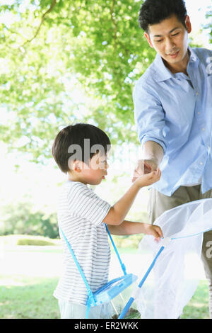 Felice giapponese padre e figlio la cattura di insetti in un parco della città Foto Stock