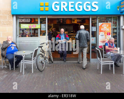 Gli uomini al di fuori di un occupato Gregg della catena panettiere e prendere via cibo e una caffetteria in Middlesbrough Cleveland Foto Stock