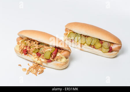 Hot Dog in un panino con cipolle arrosto, sottaceti, ketchup e senape su sfondo bianco Foto Stock